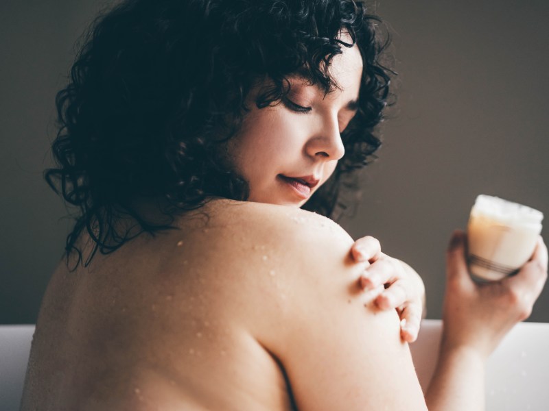 Frau cremt ihren Körper ein