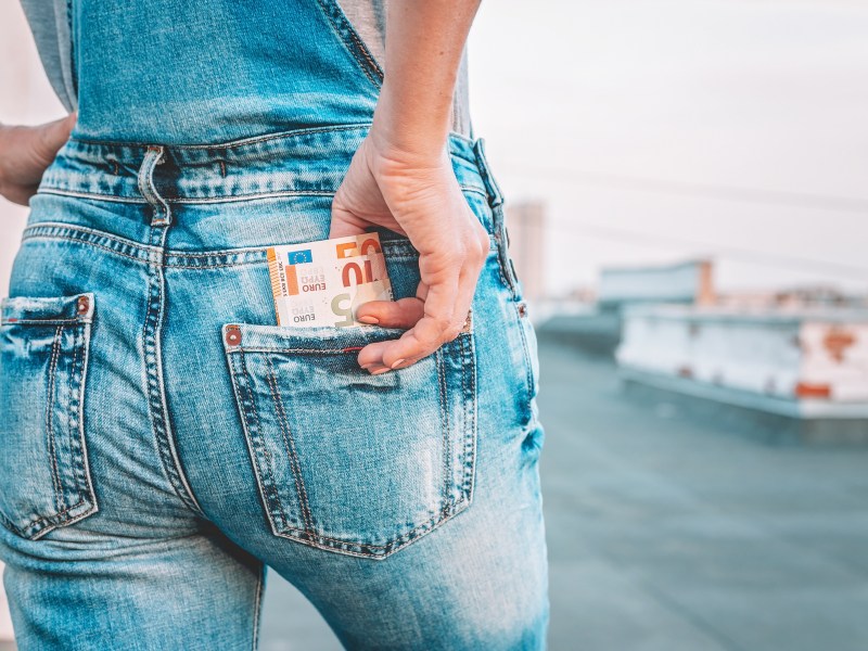 Die Hand einer Frau holt Euro-Scheine aus der GesÃ¤ÃŸtasche ihrer Jeans.