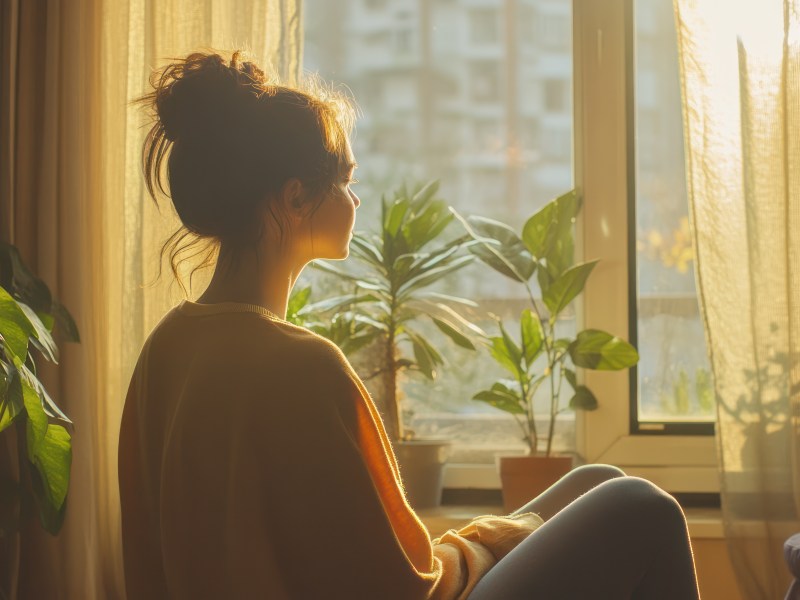 Frau meditiert vor dem Fenster