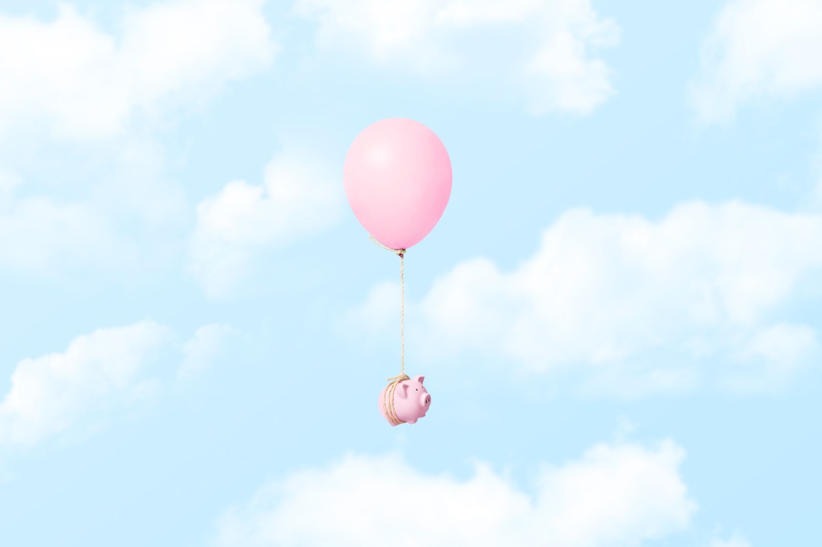Ein einzelnes rosa Sparschwein, das an einem Ballon mit einem Seil befestigt ist, das durch die Wolken schwebt.