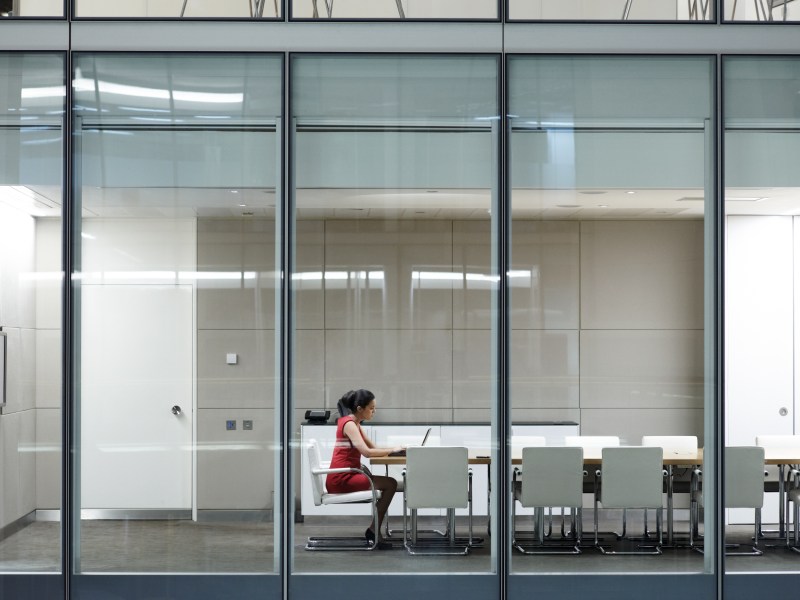 Eine Frau sitzt alleine in einem Meeting-Raum.