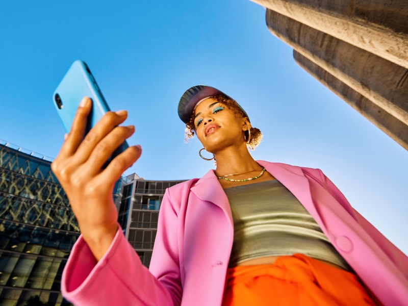 Eine Frau in bunten Klamotten bezahlt per Handy.