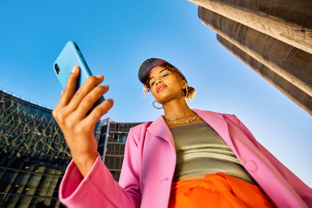 Eine Frau in bunten Klamotten bezahlt per Handy.