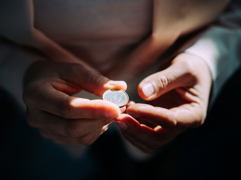 Frau hält mit beiden Händen eine Ein-Euro-Münze.