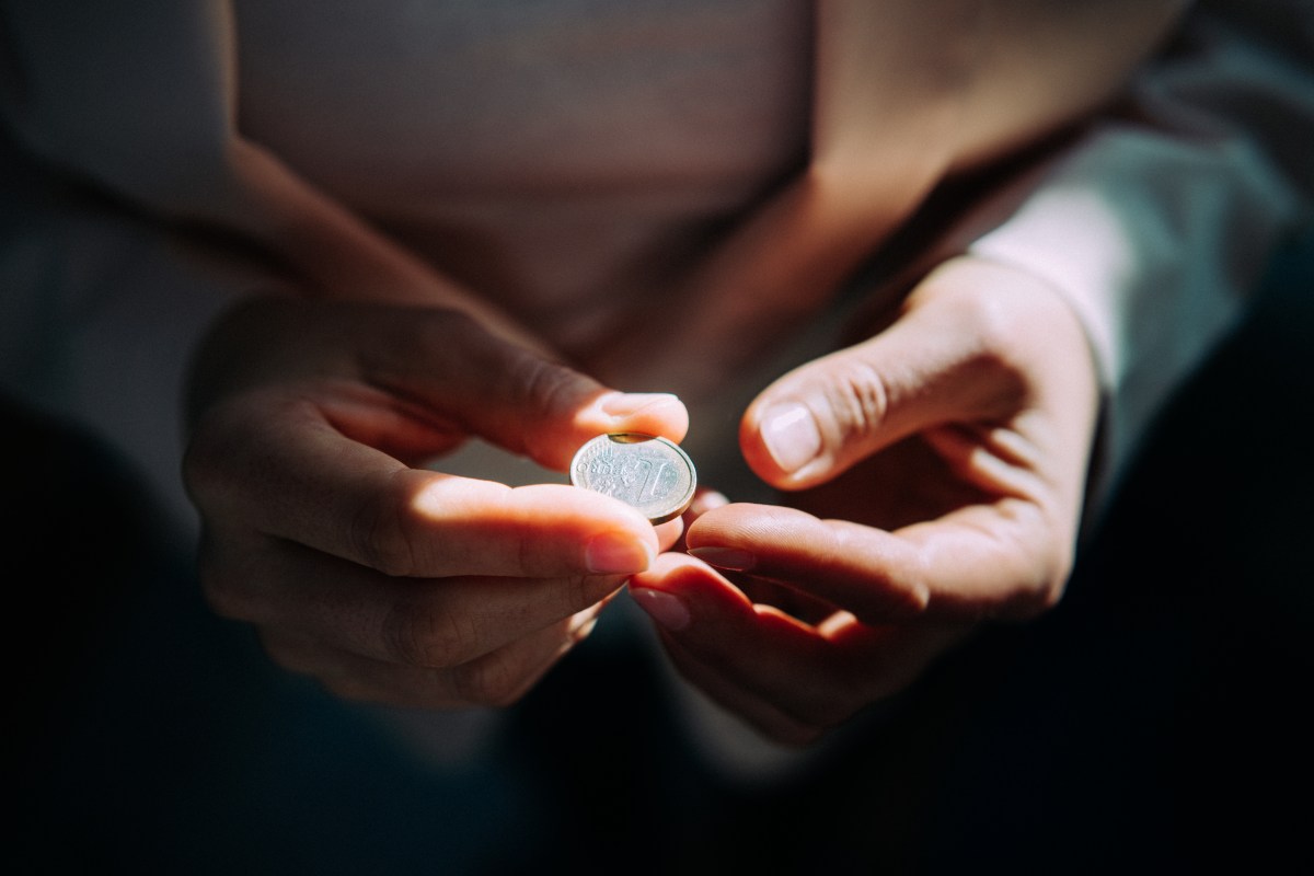 Frau hält mit beiden Händen eine Ein-Euro-Münze.