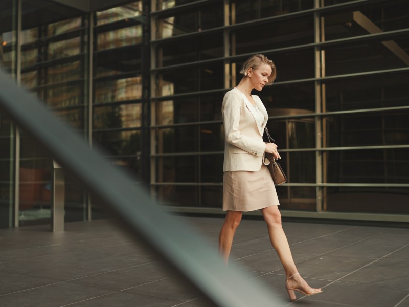 Geschäftsfrau mit blonden Haaren und beigem Anzug verlässt das Unternehmen.