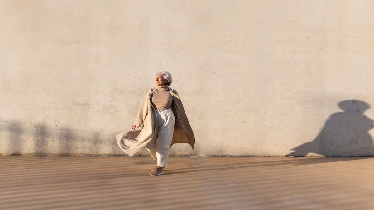 Eine Seniorin vor beigen Hintergrund.