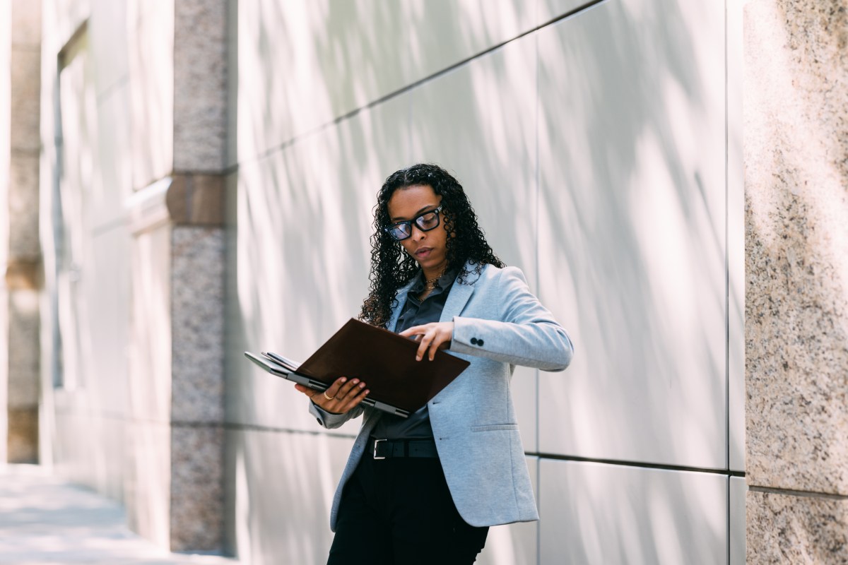 Frau prüft Dokumente vor dem Büro.