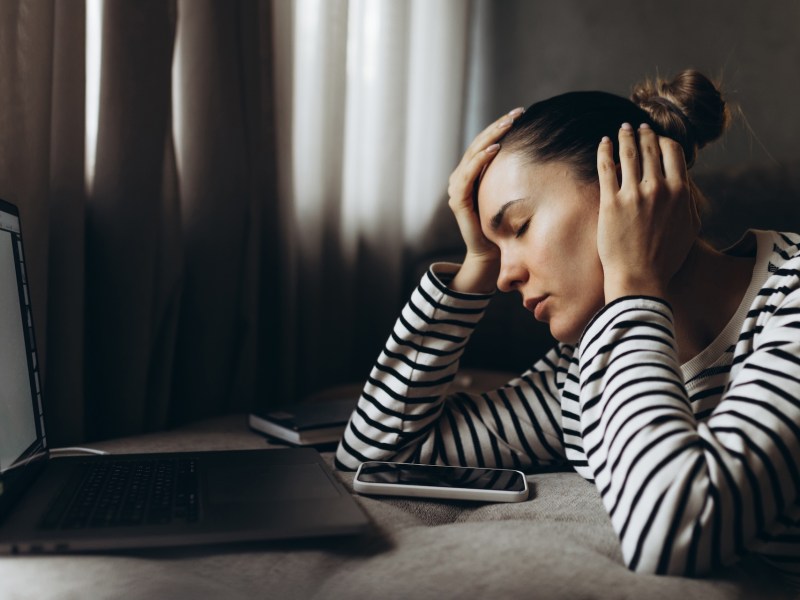 Eine Frau schaut deprimiert auf ihren Laptop.