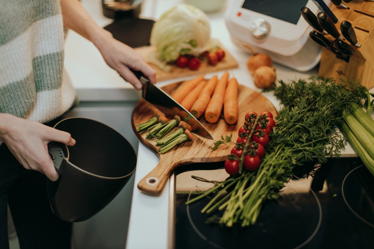 Nahaufnahme einer Frau, die Kompostabfälle trennt, während sie Gemüse schneidet.