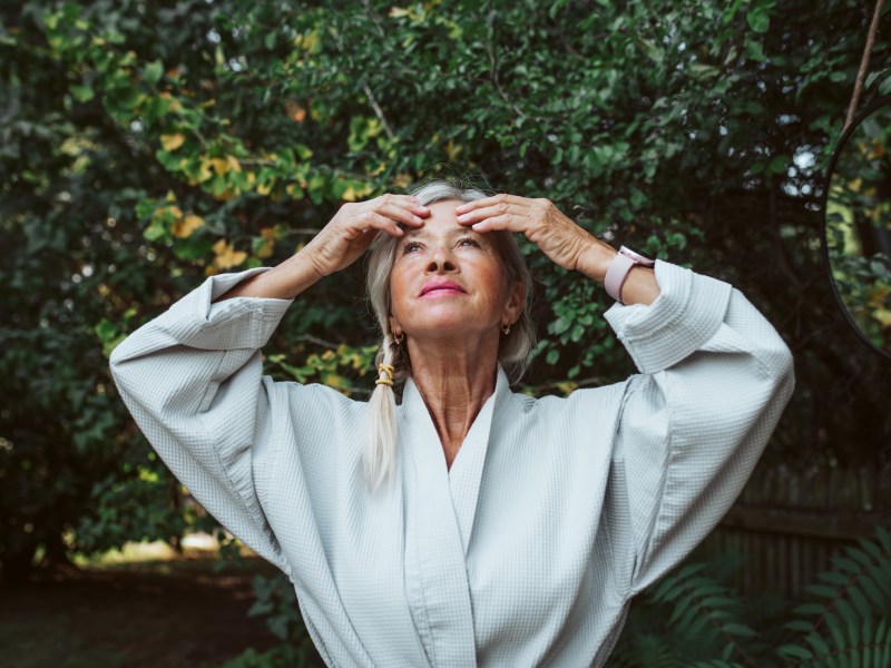 Ältere Dame streicht sich durchs Gesicht.