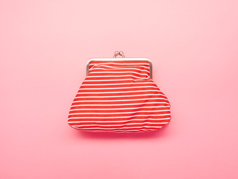 Ansicht einer rot-weiß gestreiften Brieftasche auf rosafarbenem Hintergrund.