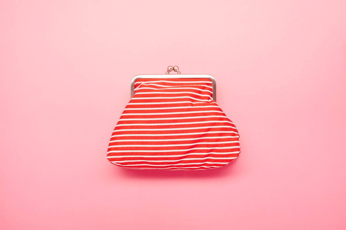 Ansicht einer rot-weiß gestreiften Brieftasche auf rosafarbenem Hintergrund.