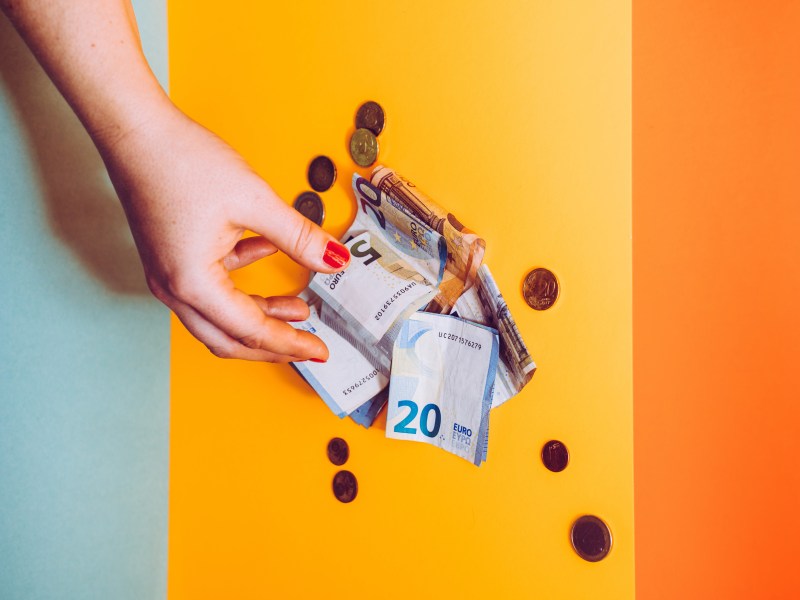 Eine Hand greift nach einem Geldschein.