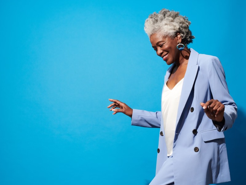 Nahaufnahme Porträt einer älteren Frau vor blauem Hintergrund.