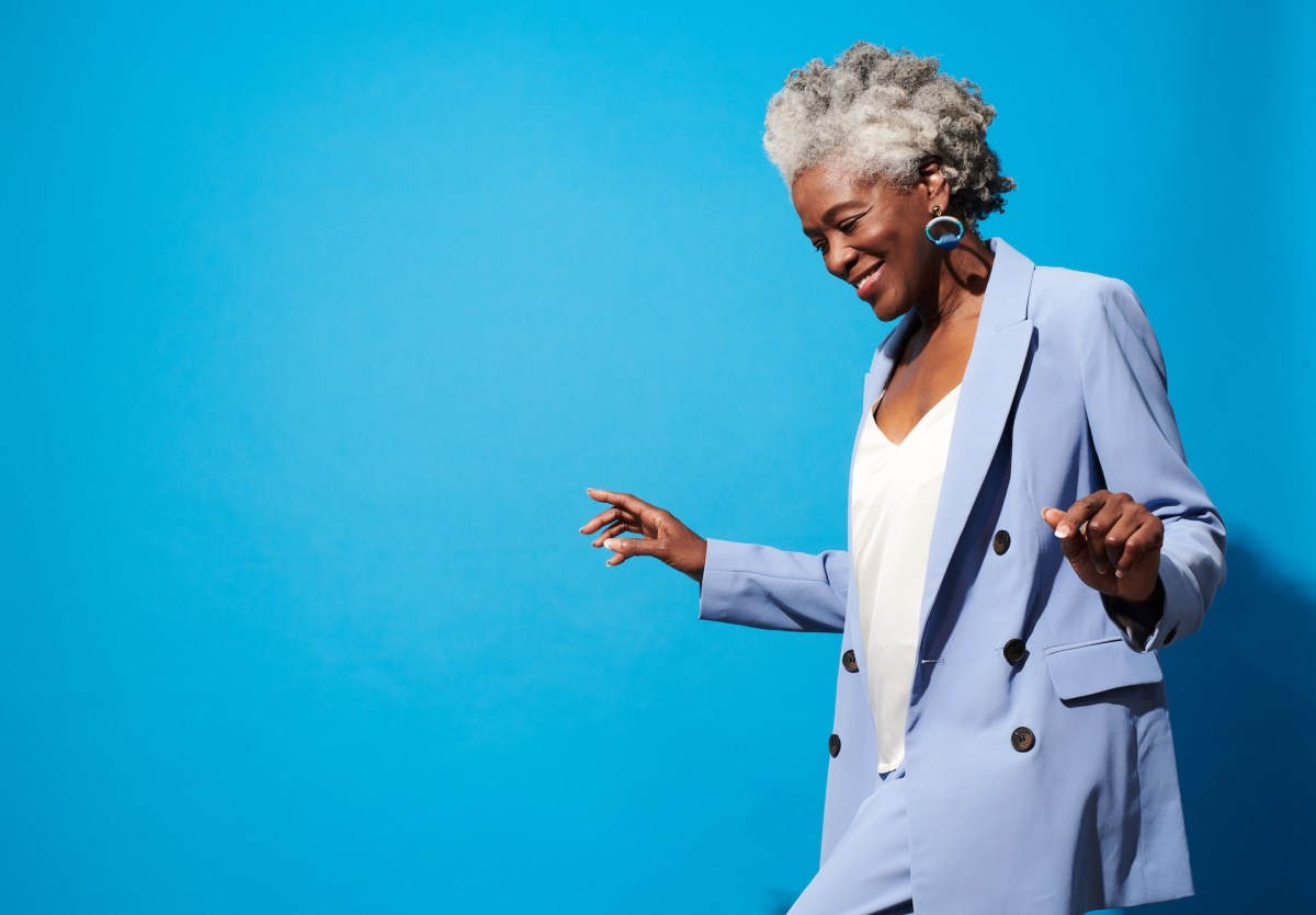 Nahaufnahme Porträt einer älteren Frau vor blauem Hintergrund.