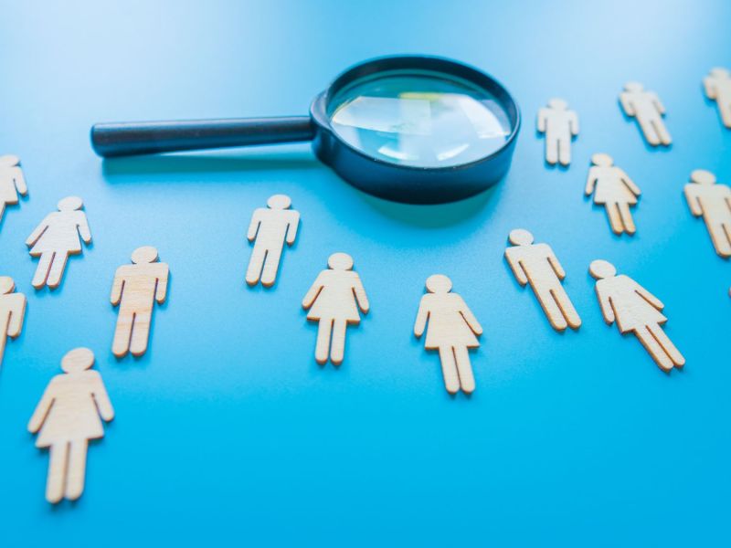 Eine Lupe und Frauen aus Papier.