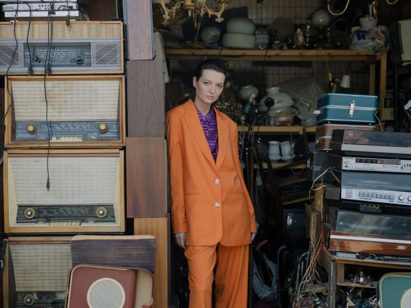 Frau steht vor einer Garage mit vielen Vintage-Sachen.