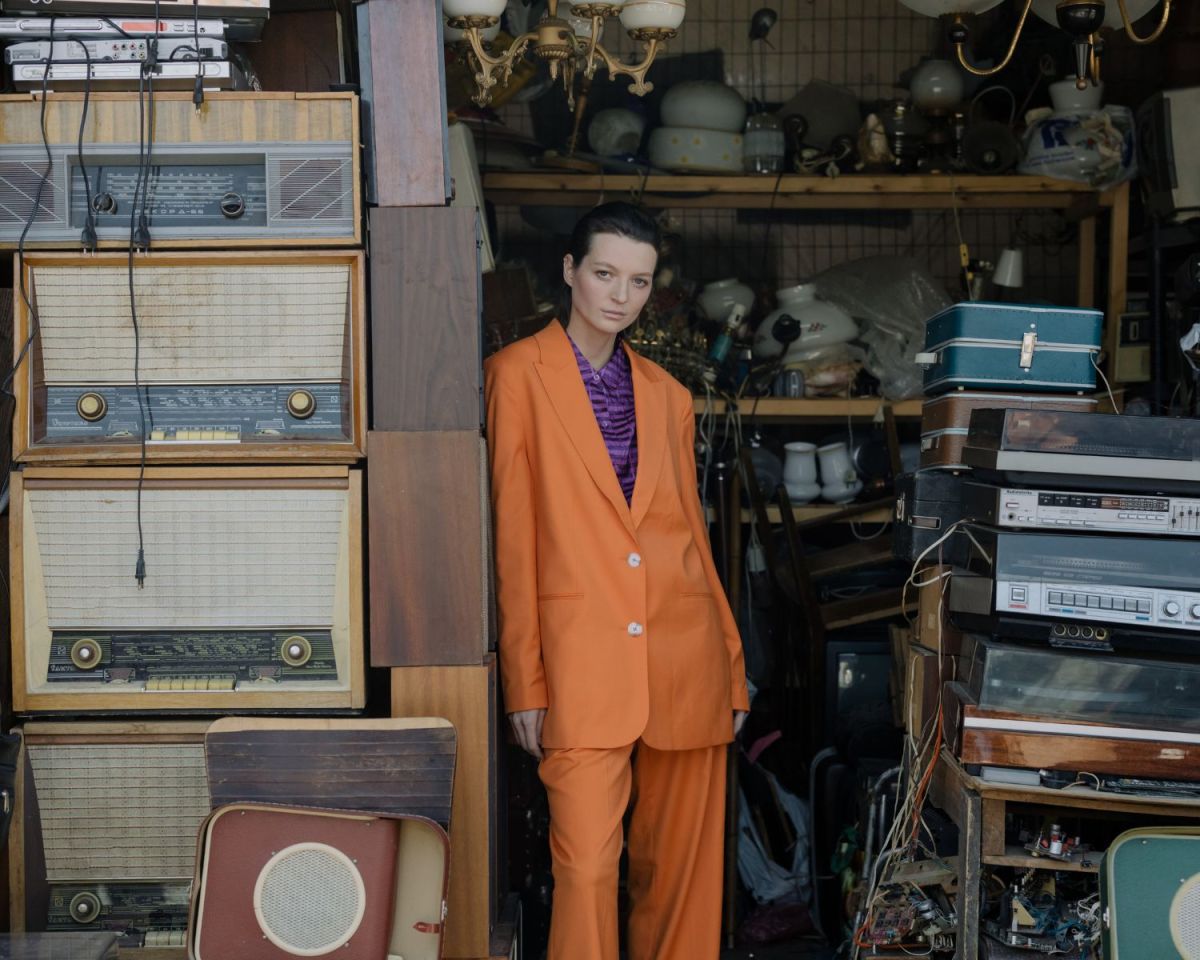 Frau steht vor einer Garage mit vielen Vintage-Sachen.