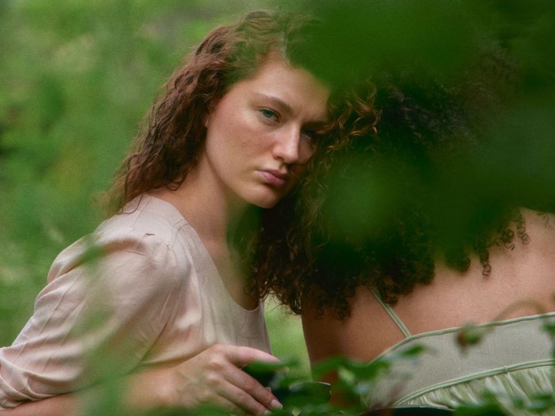 Frau lehnt sich an eine andere Frau und schaut in die Kamera.