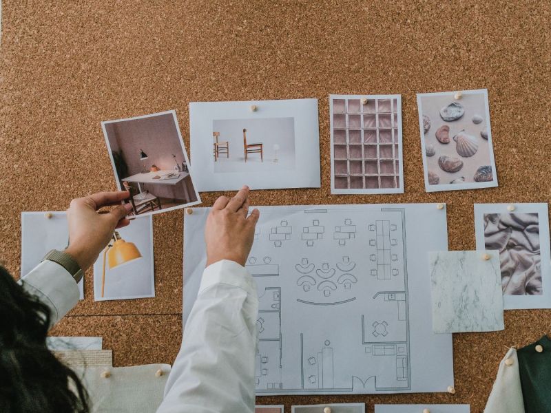 Frau steckt Interior-Bilder an ein Kork-Board.