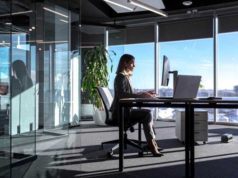 Silhouette einer Geschäftsfrau, die am Schreibtisch sitzt.