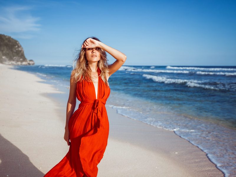 Frau mit rotem Kleid am Strand
