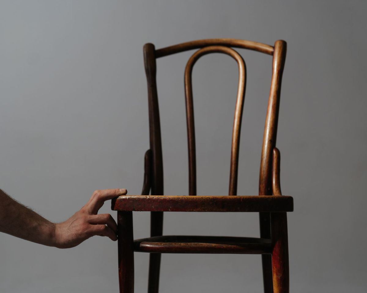Hand berührt einen Holzstuhl