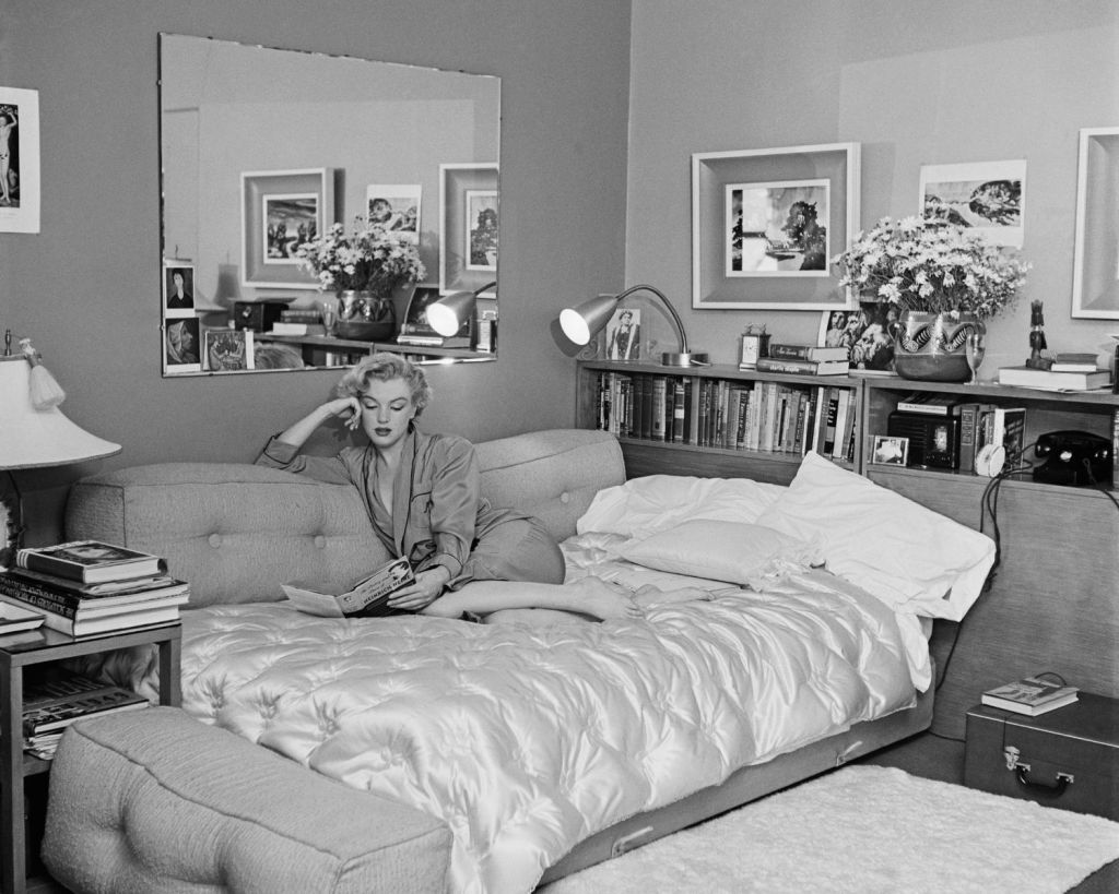 Marilyn Monroe liest etwas auf ihrem Schlafsofa