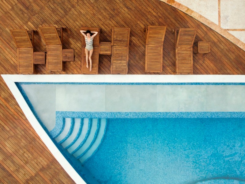 Luftaufnahme einer Frau, die sich am Swimmingpool entspannt.