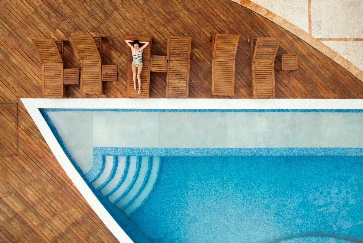 Luftaufnahme einer Frau, die sich am Swimmingpool entspannt.