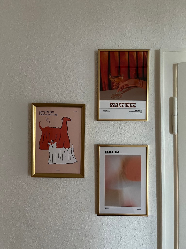 3 Poster an der Wand in einem Flur.