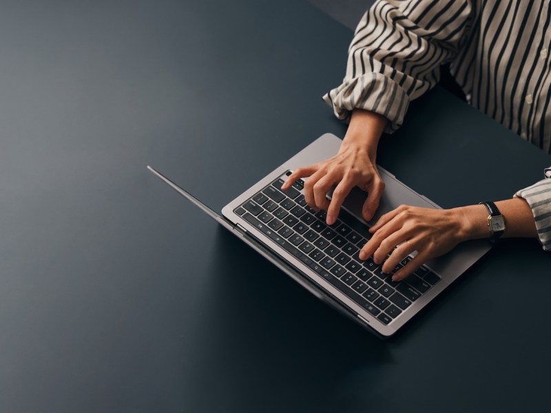 Eine Texterin, die an ihrem Schreibtisch sitzt und auf ihrem Laptop tippt.