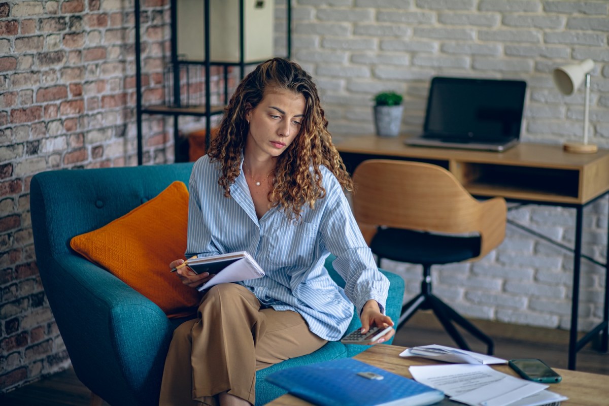 Junge Frau erledigt Papierkram im Wohnzimmer.