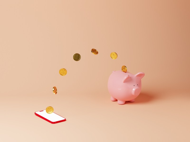 Münzen wandern von einem Handy zu einem Sparschwein.