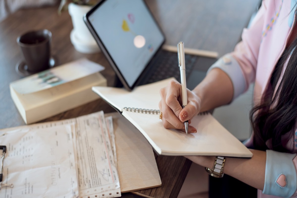 Geschäftsfrau macht sich Notizen in einem Notizbuch auf dem Schreibtisch im Büro.
