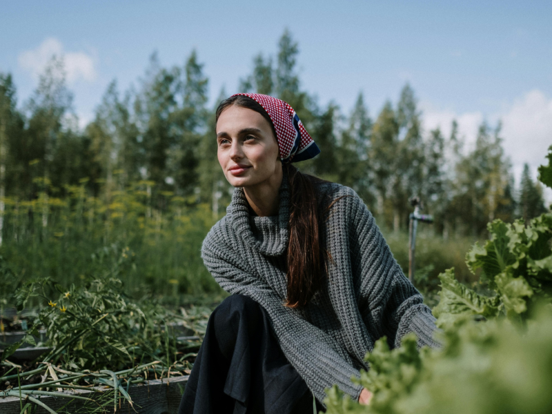 Frau kniet auf einem Feld und erntet