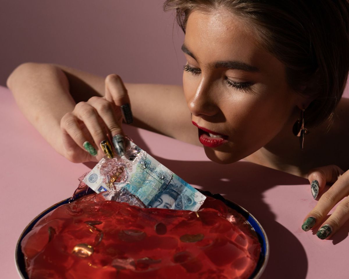 Frau nimmt einen Geldschein aus einem Wackelpudding.