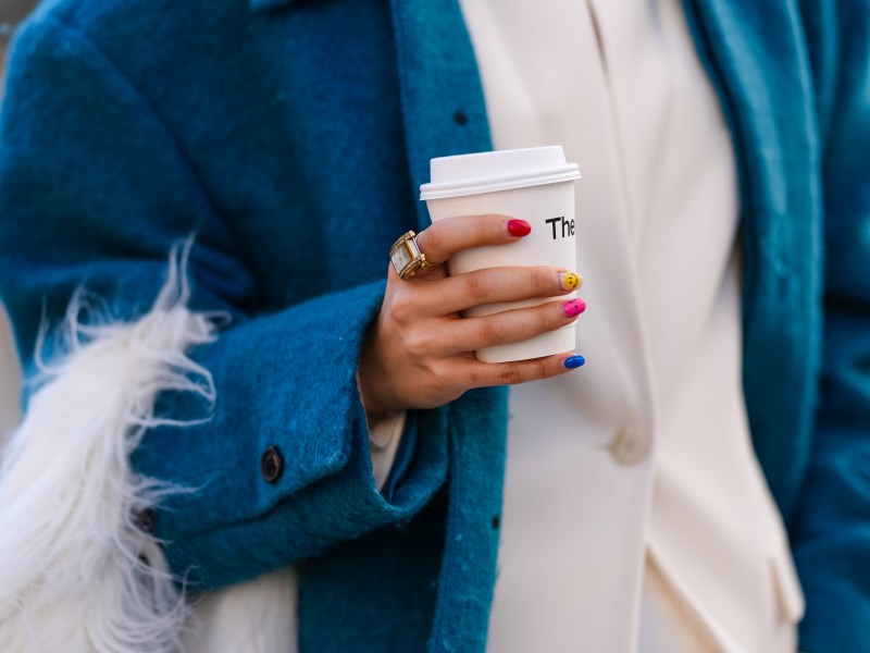 Frau mit Nägeln hält Kaffee