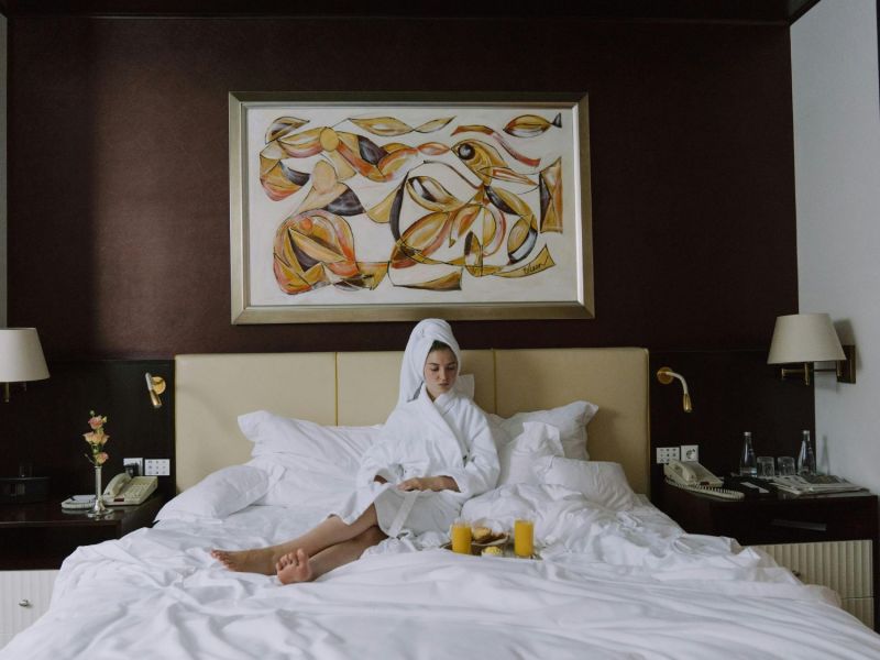 Frau sitzt in Hotelbett