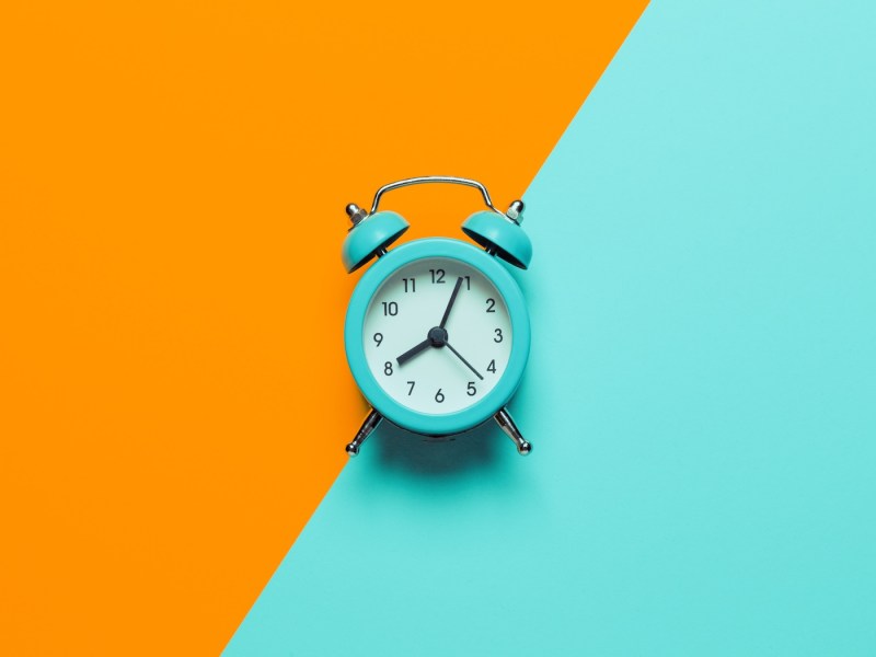 Wecker auf orange-blauem Hintergrund.