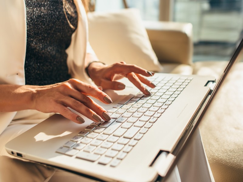 Nahaufnahme der Hände einer Frau, die auf der Laptoptastatur tippt.