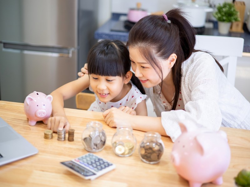 Mädchen und ihre Mutter lernen Mathematik mit Bargeld und Geldplanung.