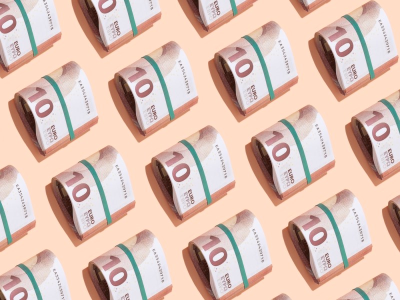 Mehrere 10-Euro-Schein-Rollen auf rosa Hintergrund.