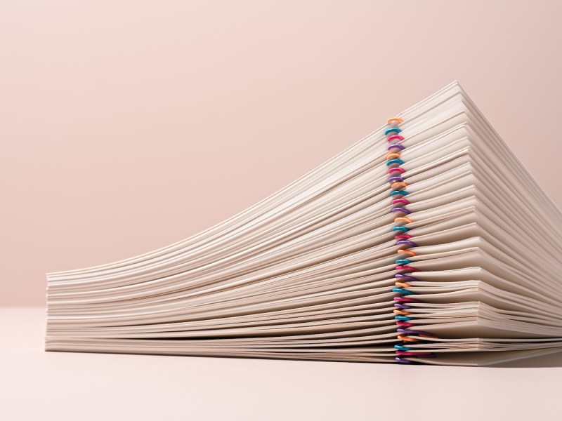 Gestapelte Papierdokumente, organisiert mit bunten Büroklammern.