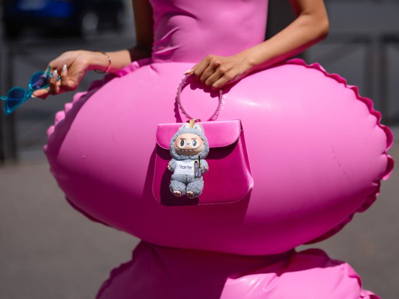 Frau in Pink trägt einen labubu an ihrer Tasche