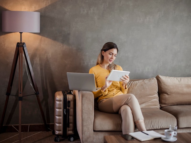 Geschäftsfrau nutzt digitales Tablet, während sie auf Geschäftsreise vom Hotelzimmer aus arbeitet.