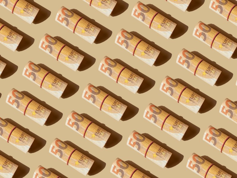 Viele 50-Euro-schein-Rollen auf beigen Hintergrund.