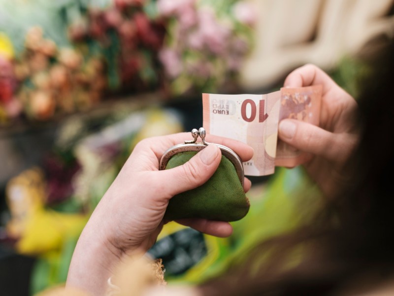 Nahaufnahme einer Frau, die einen 10-Euro-Schein in der Hand hält.