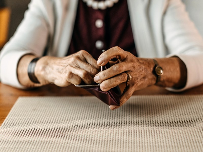 Alte Frau zählt Münzen aus ihrer Brieftasche.